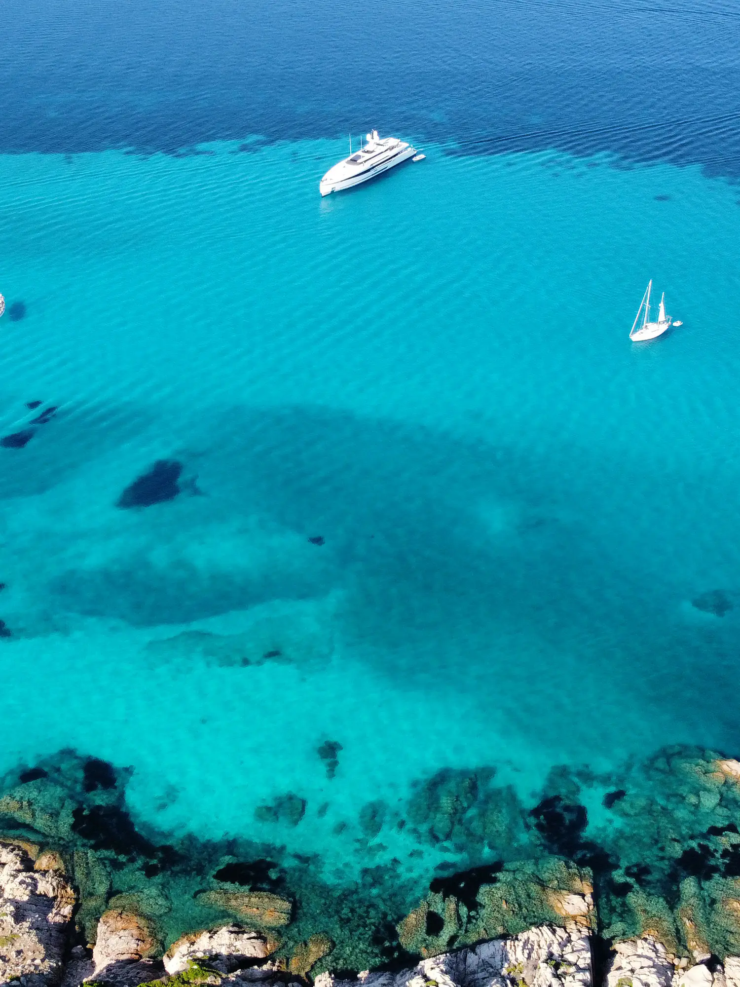 A superyacht at anchor in a turquoise bay